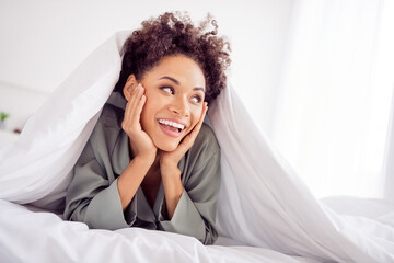 Portrait of attractive cheerful girl lying in bed under duvet good mood enjoying pastime at light home house indoors