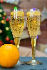 Two glasses of champagne and bright juicy oranges on background of an elegant Christmas tree, the concept of the new year.