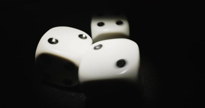 Plastic playing gambling dice rolling forever against dark background
