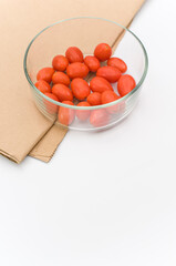 fresh organic datterini tomatoes in a glass bowl on a white tabletop