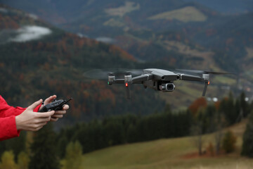 Fototapeta na wymiar Woman operating modern drone with remote control in mountains, closeup