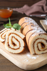 Tasty cake roll with jam on wooden table
