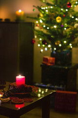 Home interior with the lights off, decorated for the New Year with a Christmas tree, gifts, lights, candles