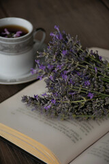 Fototapeta na wymiar Moscow, Russia, June 2021, a bouquet of lavender lies on an open book against the background of a cup, still life