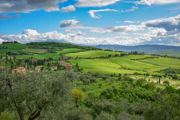 Tuscany, Italy, 2019, view of the green valley from above and yellow-orange farm houses
