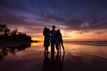 Silhouettes of big happy family on beach during sunset
