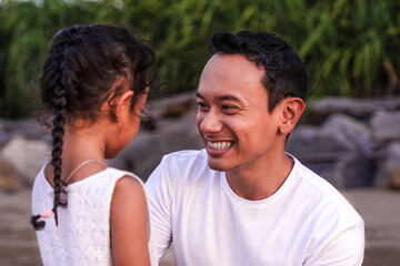 holidays, children and family concept - happy father communicating with his little daughter outdoor