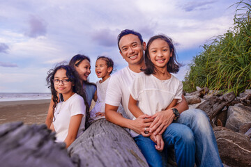 family, leisure and people concept-portrait of big asian family with three daughters sitting on the wood, enjoying summer vacation together