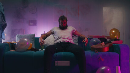 Fototapeta premium Bearded man sitting on sofa during party