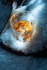 a glass of whiskey in the snow. concept of a warming drink on a cold winter evening.