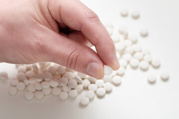 Fototapeta na wymiar One white round pill in a hand. Vitamin pills.