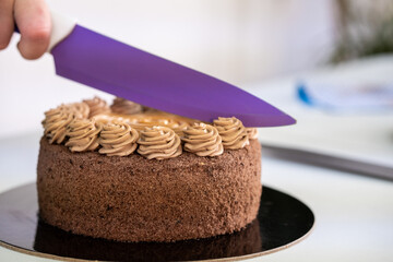 Slicing a delicious and gorgeous fancy chocolate caramel cake.