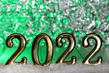 Gold numbers 2022 on snow with green backlight. New year backdrop with 2022 year