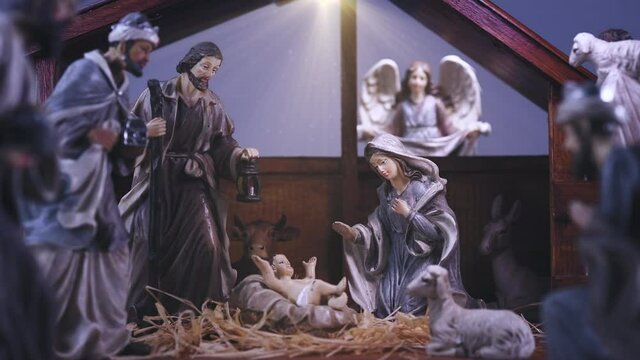 Jesus Christ Nativity scene with figurines in stable and light particles. Jesus Christ birth in a manger with Mary and Joseph. Christmas scene. Dolly shot 4k
