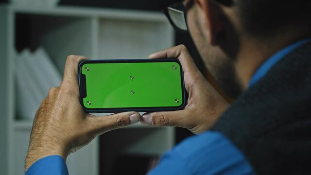 Man Using Smartphone in Horizontal Mode with Green Mock-up Screen