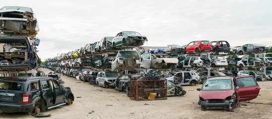 Old rusty corroded and crushed cars in car scrapyard. Car recycling.  Ecological concept by dump of wrecked cars.