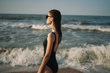 woman in black swimsuit walking on the beach ocean summer