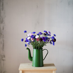 Bouquet cornflowers in watering can on table