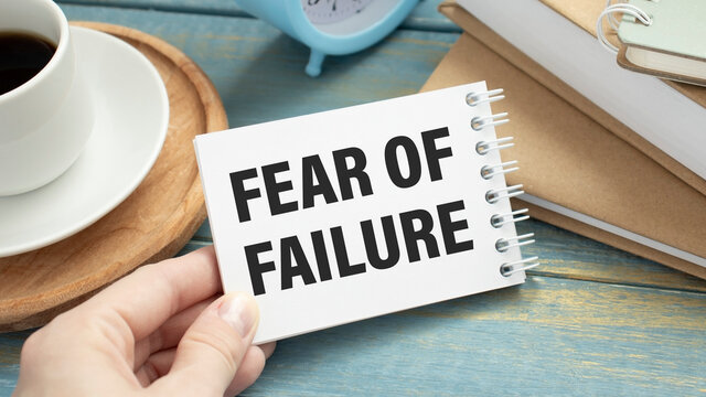 take a paper with text Fear of Failure on the shirt with office background