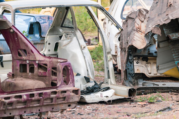 Metal broken cars body parts abandoned outdoors. Car dump, wreck at a junkyard ready for recycling. Atmospheric weathered auto junk