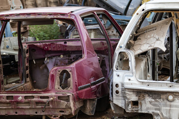 Fototapeta premium Two disassembled cars body parts outdoor close-up view. Car dump, wreck at a junkyard ready for recycling