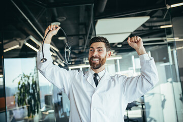 Fototapeta na wymiar Happy and successful doctor in a white medical gown, dancing with joy, satisfied with the result of his work, rapid recovery of the patient, in a modern clinic