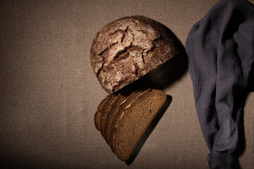 rye sliced bread and a gray towel lies on a linen tablecloth