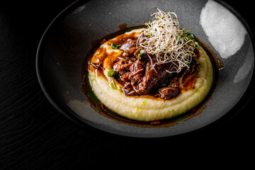 Stewed veal cheeks with mashed potatoes on plate on rustic wooden table dark background - obrazy, fototapety, plakaty