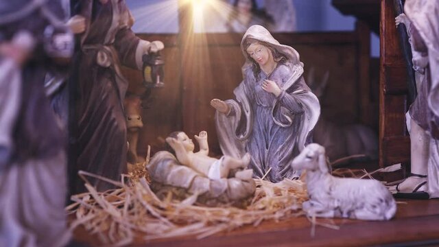 Jesus Christ Nativity scene with figurines in stable and light particles. Jesus Christ birth in a manger with Mary and Joseph. Christmas scene. Dolly shot 4k