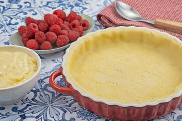 préparation d'une délicieuse tarte aux framboises entières, ingrédients sur table