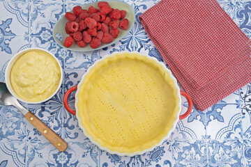 préparation d'une délicieuse tarte aux framboises entières, ingrédients sur table