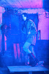 portrait in neon light of a beautiful girl in an abandoned building with a metal pipe in her hands