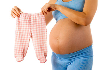 pregnant woman tries on baby clothes on her belly. woman on white background. 