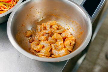 Close up of a metal bowl with fresh marinated shrimps
