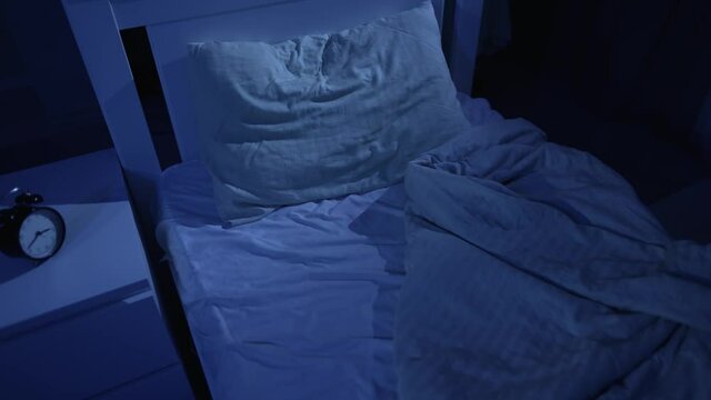 Empty unmade bed at night