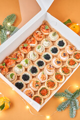 Black and Red caviar with butter in tartlets, crispy shrimps with lemon in sauce in take way box. Menu food for delivery in the Coronavirus Pandemic