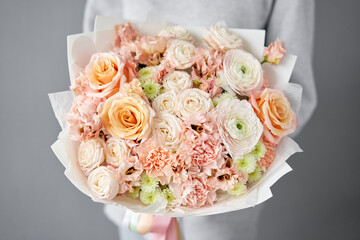 Flower arrangement in Wicker basket. Beautiful bouquet of mixed flowers in woman hand. Handsome fresh bouquet. Small flower shop and Flowers delivery.