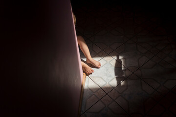 Legs of small child sitting on the floor in pocket of light