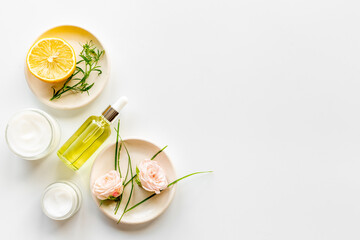 Fototapeta na wymiar Herbal and flowers cosmetic flat lay with citrus oil and skin cream
