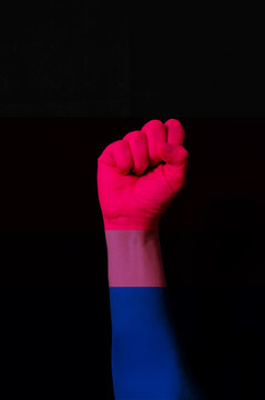 Fist hand with bisexual pride flag patterned isolate on black. L