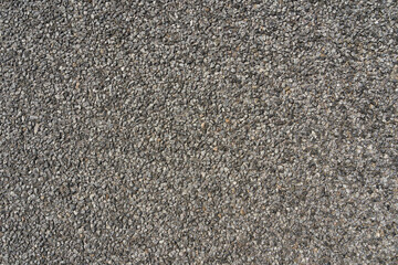 Gray small road stone background, dark gravel pebbles stone, texture, crushed granite. A fragment of the road