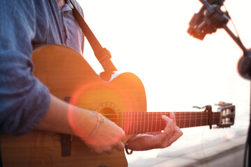Close up shot of a man playing classic guitar on sunset