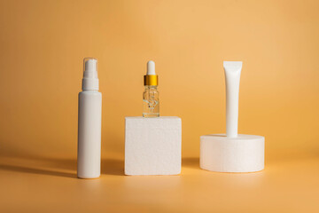 Unbranded bottle with dispenser on geometric podium stands. Unbranded bottles in mockup style. Night, day cream cosmetic oil, eye cream on yellow background. Spa, beauty, natural cosmetics concept.