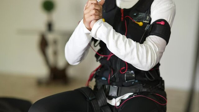 EMS training. Girl doing exercises in a suit with cables.