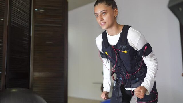 EMS training. Girl doing exercises in a suit with cables.