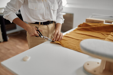 Seamstress with scissors cuts cloth in workshop