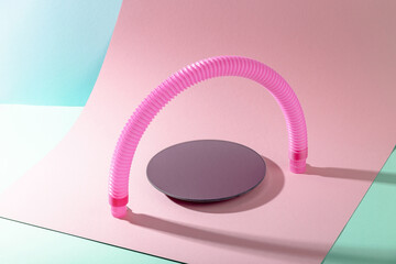 Mirror stand under pink antistress pop tube toy in shape of arch with shadow on pink and blue background. Bright kid toy. 