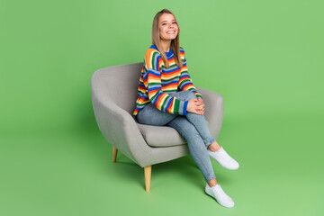 Full length body size photo smiling girl sitting in grey chair wearing casual clothes isolated pastel green color background