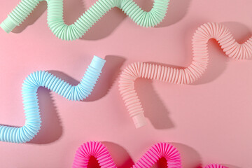 Curved pink blue mint antistress pop tube toy with shadow on pink background. Bright kid toy. Wallpaper 