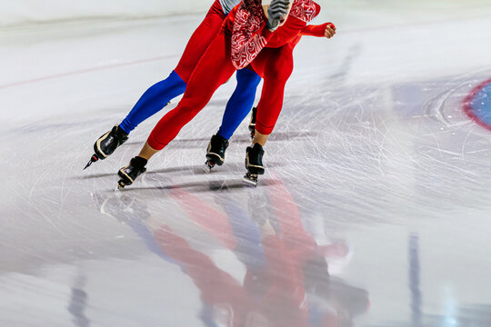 two male speed skaters running in ice ring